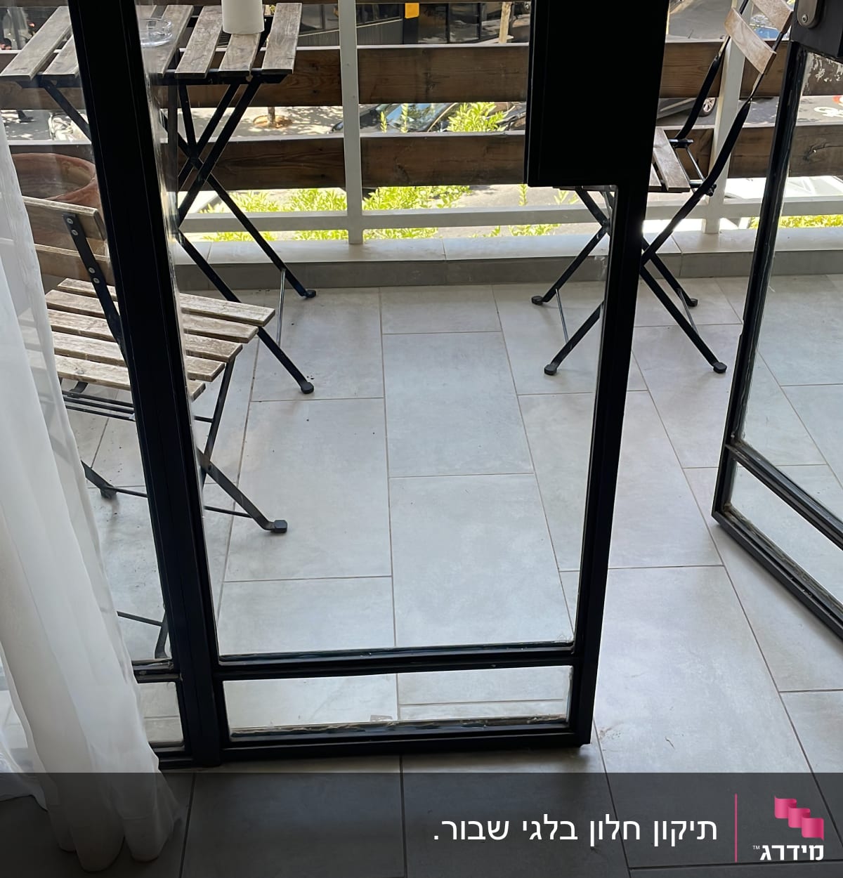 דלת זכוכית פתוחה למרפסת עם שולחן וכיסאות